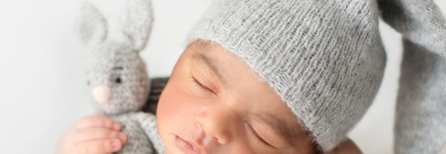 cute-infant-sleeping-with-grey-crocheted-hat-with-toy-rabbit 1